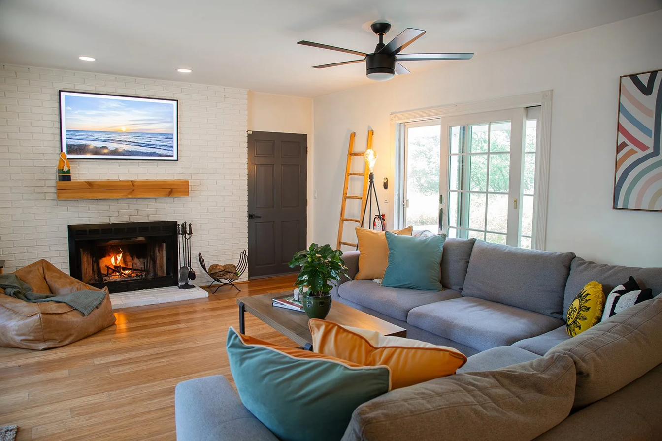 Living room with whitewashed brick wood-burning fireplace and large sectional