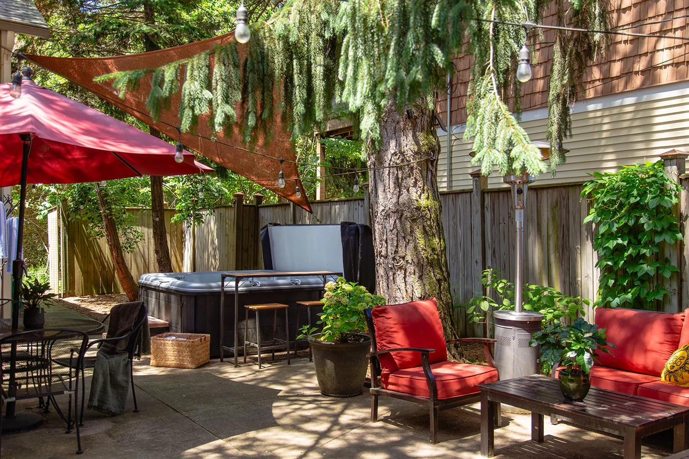 Six-person hot tub under string lights in the fenced backyard