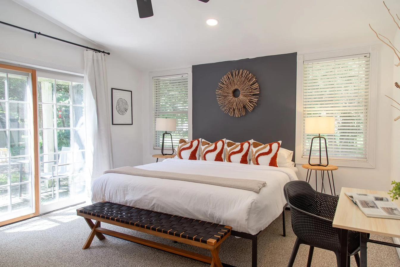 Primary bedroom with king bed, charcoal accent wall and driftwood sunburst mirror