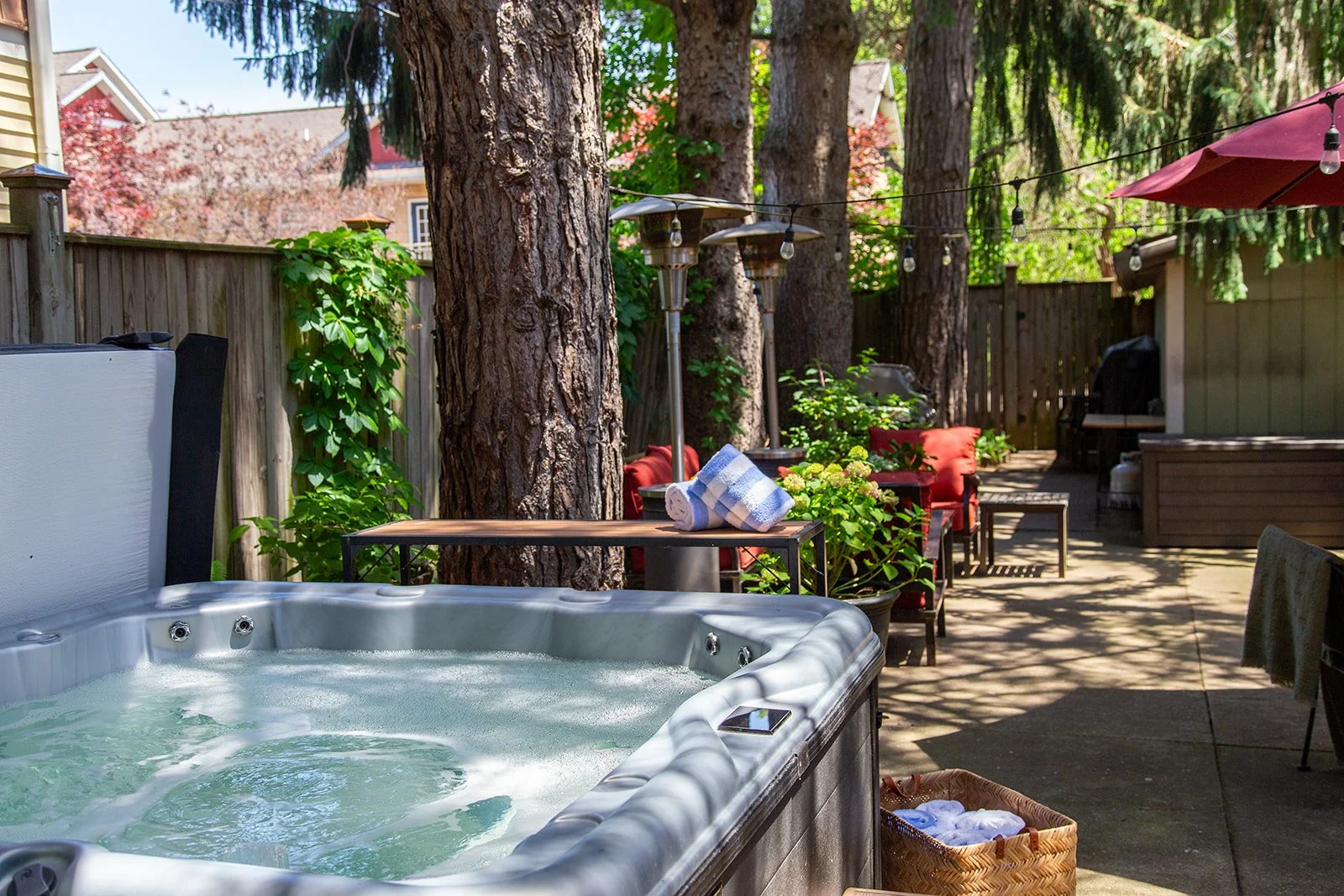 The year-round hot tub under the pines, string lights glowing at dusk